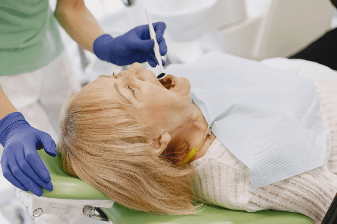 an old woman wearing a white shirt at a dentist getting her teeth checked