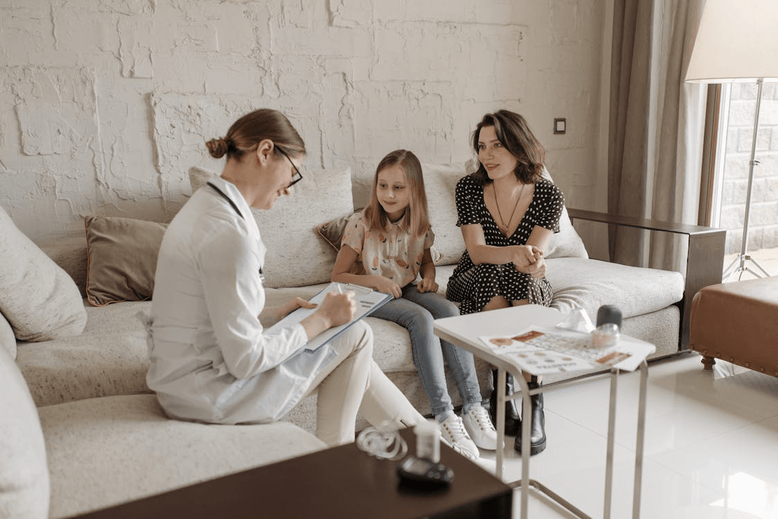 a doctor giving consultation to a little girl and her mother at their house