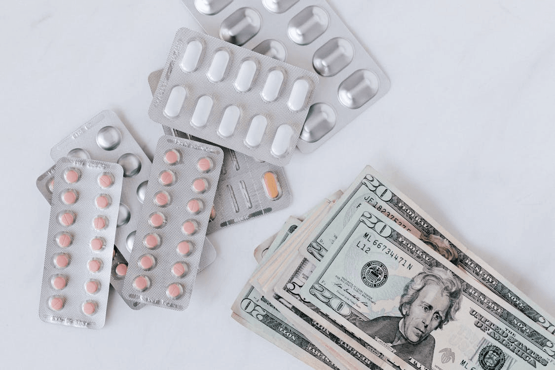 a top-view of medicine pills stacked on each other and a pile of money