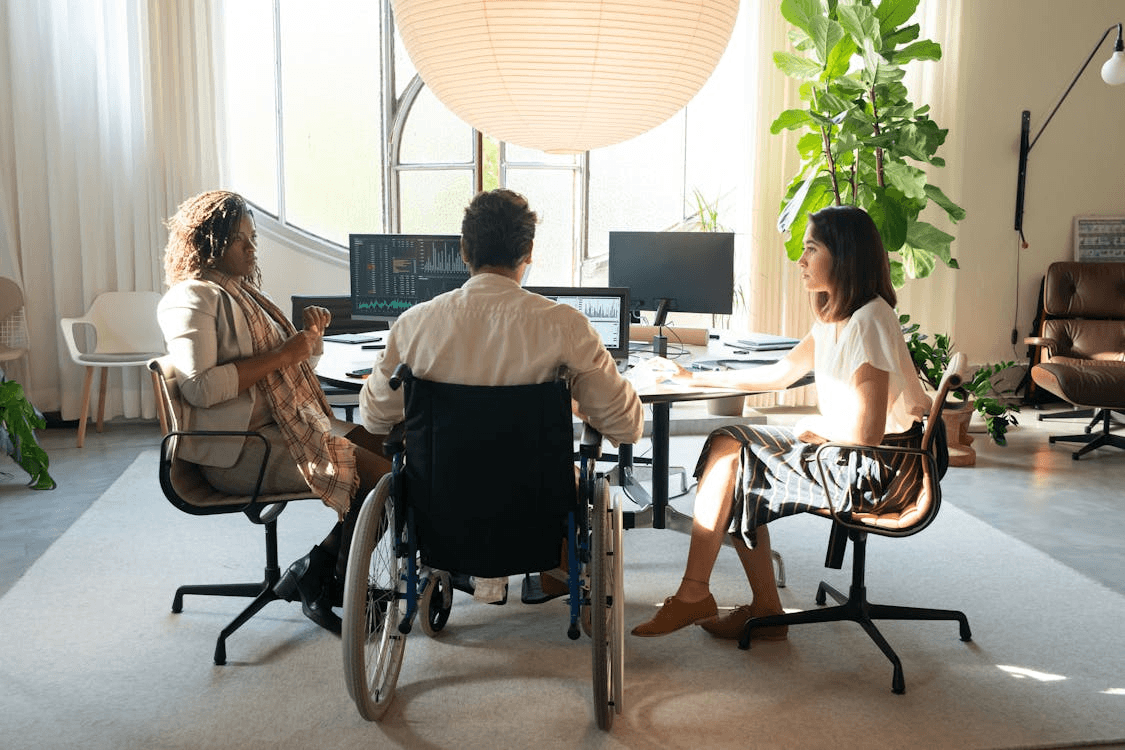 a person in a wheelchair at an insurance meeting with two women