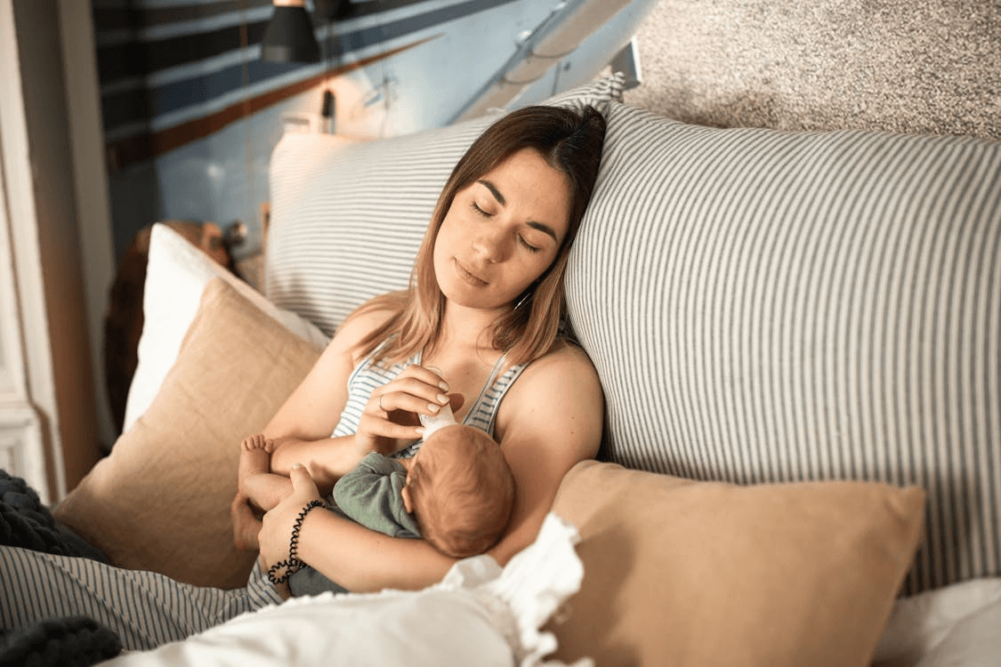 a mother with a newborn baby, tired and sleepy while feeding
