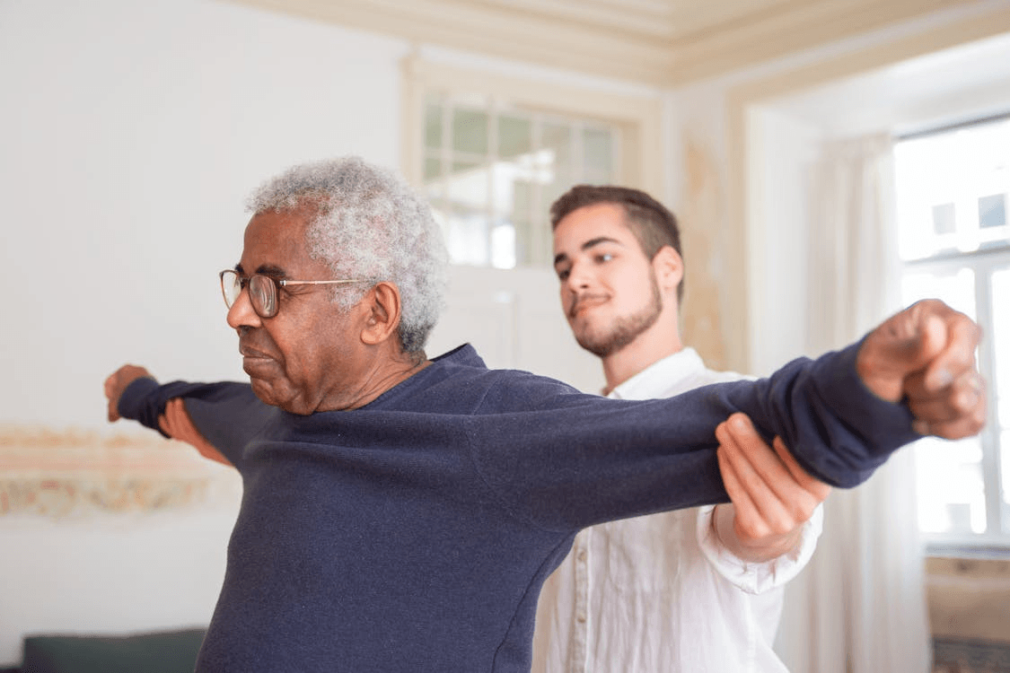 a caretaker at an elderly man’s house helping him with physical therapy