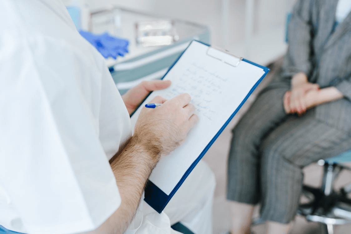a doctor wearing a white coat using a clipboard to write the patient sitting a prescription