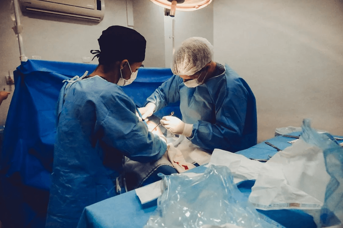 doctors in blue clothes and masks performing a surgery in a hospital room
