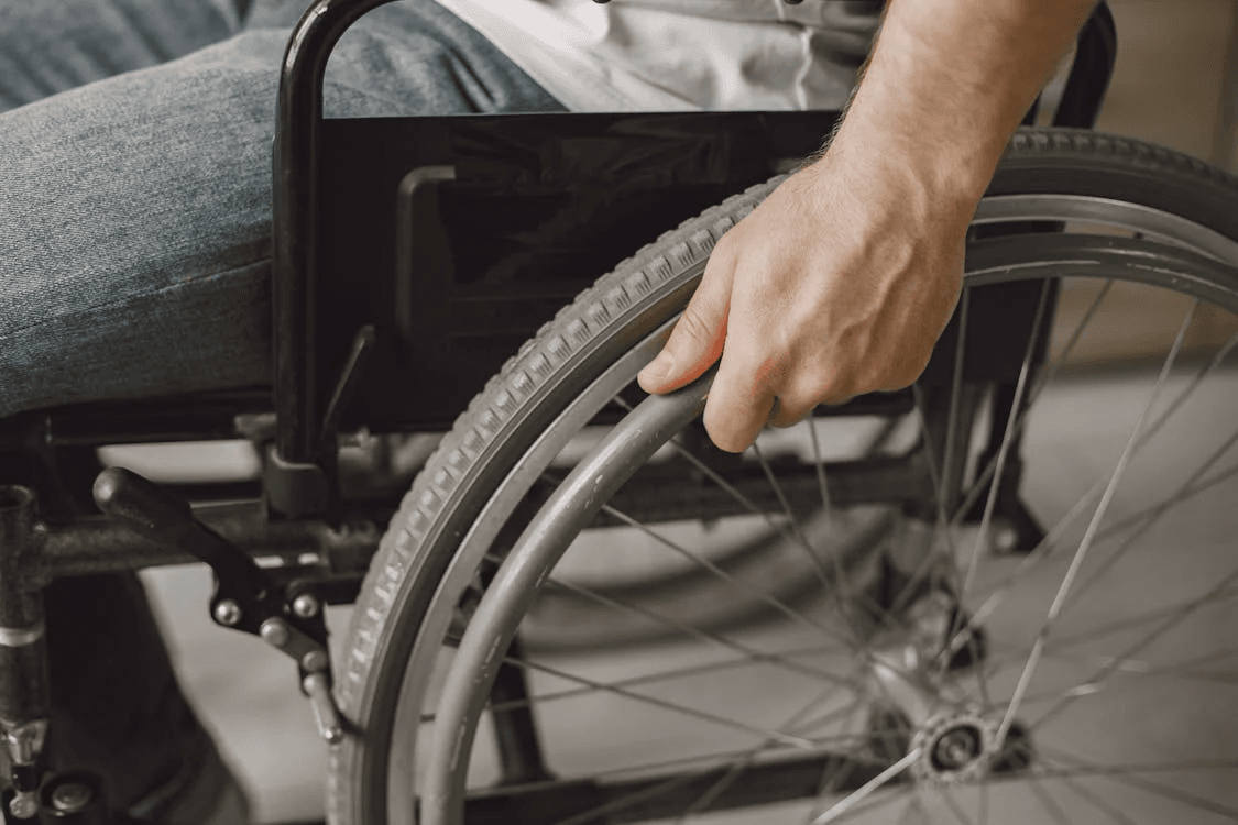 close-up shot of the wheel of the wheelchair with a man on it