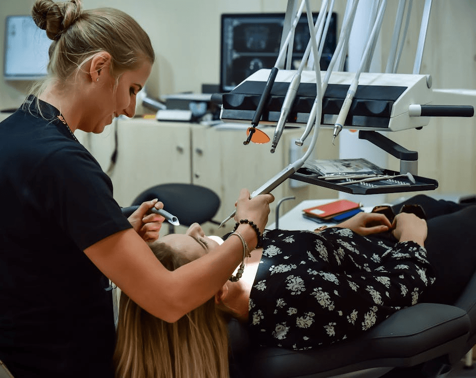 woman at a dentist's office getting her teeth examined while lying on the dentist's bed