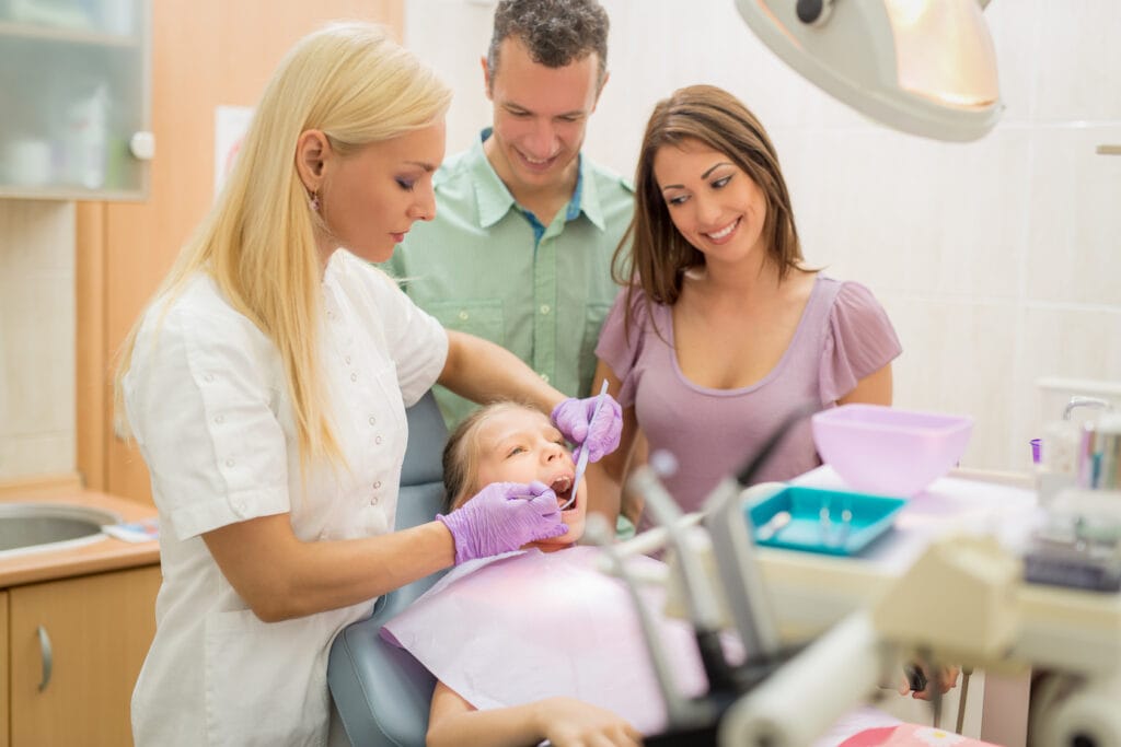Dentist treating a child with parents present for Dental Insurance Plans in Texas.