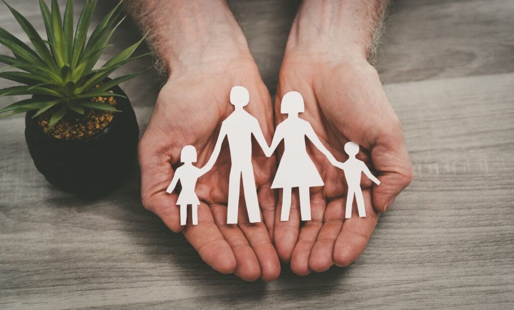 Life Insurance Plans in Texas image showing hands holding family cutout symbolizing protection for business owners.
